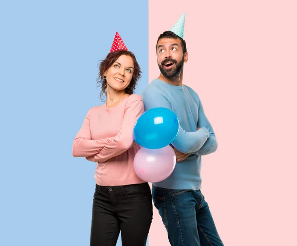 Coppia Con Palloncini Cappelli Compleanno Guardando Alto Sorridendo Sfondo Rosa — Foto Stock