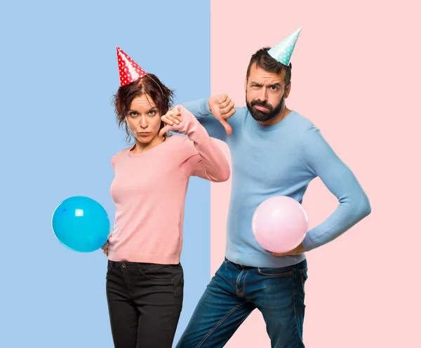 Pareja Con Globos Sombreros Cumpleaños Mostrando Pulgar Hacia Abajo Signo —  Fotos de Stock