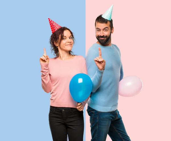 Couple Avec Des Ballons Des Chapeaux Anniversaire Montrant Levant Doigt — Photo