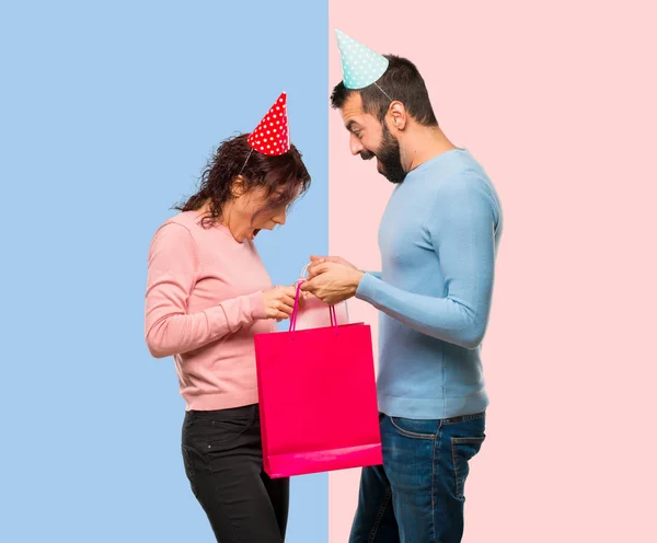 Pareja Con Sombreros Cumpleaños Con Bolsas Compras Sobre Fondo Rosa — Foto de Stock