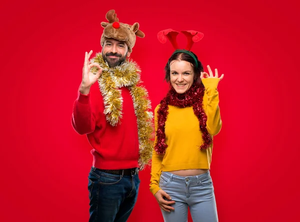 Pár Oblečená Pro Vánoční Svátky Zobrazeno Znaménko Prsty Izolované Červeném — Stock fotografie
