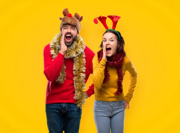 Couple Dressed Christmas Holidays Shouting Lateral Announcing Something Yellow Background — Stock Photo, Image