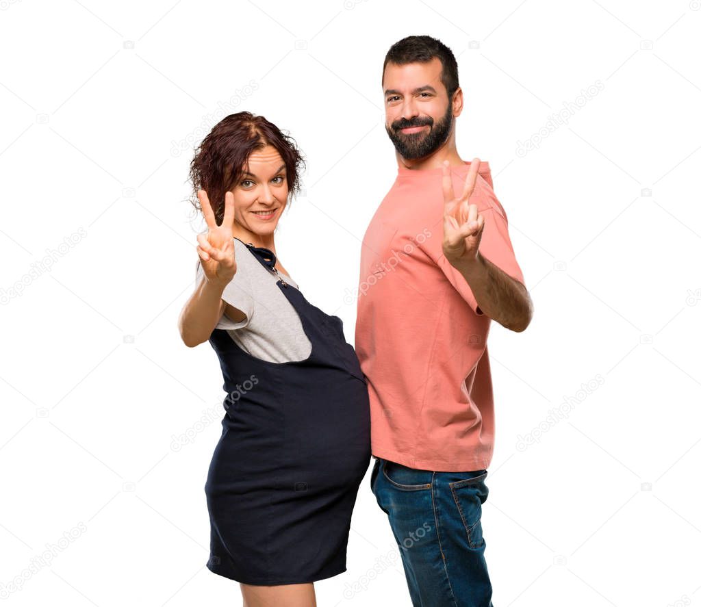 Couple with pregnant woman smiling and showing victory sign on isolated white background