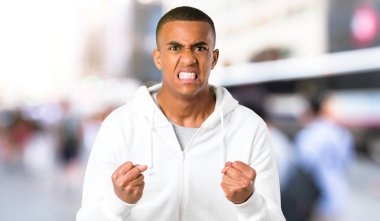 Genç adam koyu tenli beyaz kazak ile Öfkeli öfkeli jest olarak rahatsız. Açık kötü bir durumda sinirli