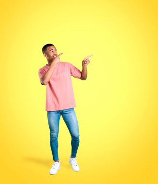 Harika bir fikir işaret parmağı ile işaret ve renkli arka plan üzerinde ararken genç Afro-Amerikan adam ayakta