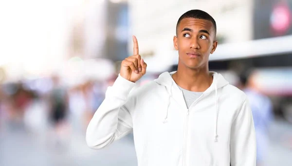 黑皮肤的年轻人 穿着白色运动衫站着 想着一个想法 把手指放在户外 — 图库照片