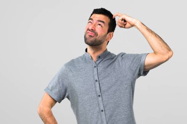 Yakışıklı adam şüpheleri ve gri arka plan üzerinde karıştırmayın yüz ifadesi ile