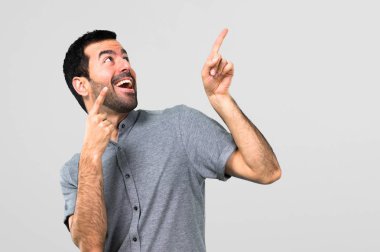 Yakışıklı adam gri arka plan üzerinde harika bir fikir işaret parmağı ile işaret