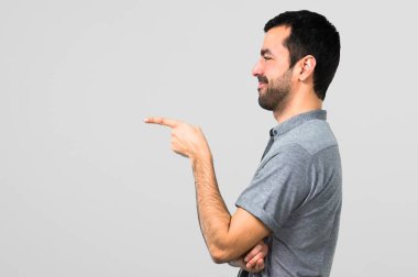 Parmak tarafına işaret ve gri arka plan üzerinde bir ürün sunma yakışıklı adam