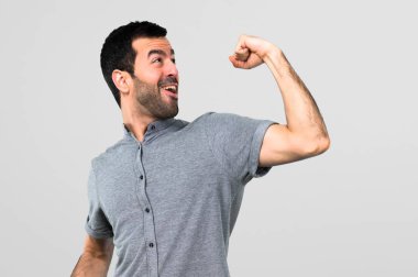 Yakışıklı adam gri arka plan üzerinde bir zafer kutluyor