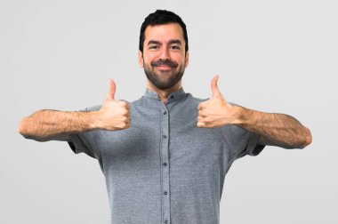 Jest Yaşasın vererek ve gri arka plan üzerinde gülümseyen yakışıklı adam