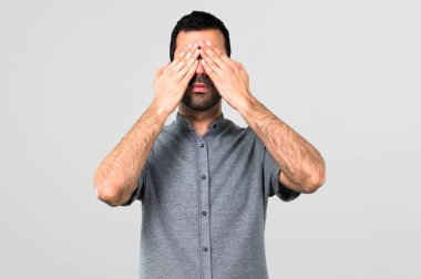 Yakışıklı adam gri arka plan üzerinde eller tarafından göz kapsayan