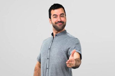 Yakışıklı adam el sıkışma gri arka plan üzerinde iyi bir anlaşma sonra