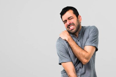 Gri arka plan üzerinde omuz ağrısı ile yakışıklı adam