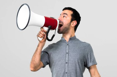 Yakışıklı adam bir megafon gri arka plan üzerinde tutan