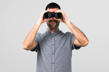 Gri arka plan üzerinde dürbün ile yakışıklı adam