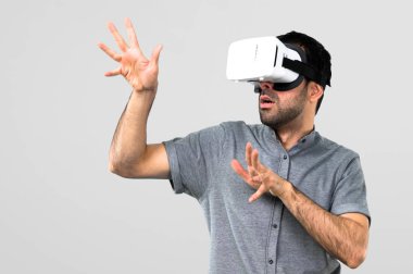Yakışıklı adam VR gözlükle gri arka plan üzerinde