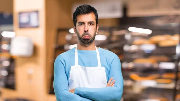 Man wearing an apron with sad and depressed expression. Serious gesture in a bakery