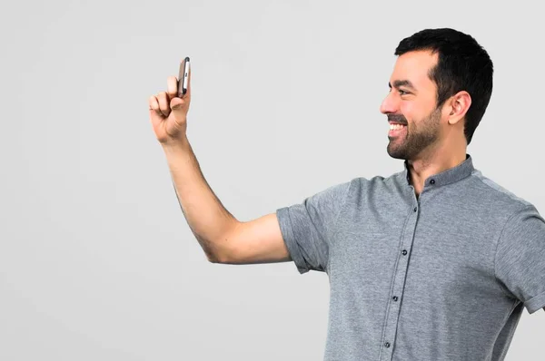 Bonito Homem Com Móvel Fazendo Uma Selfie Fundo Cinza — Fotografia de Stock