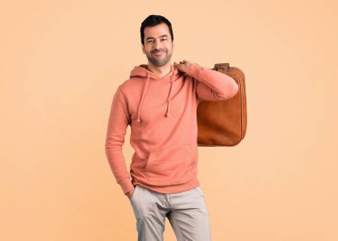 Pembe bir kazak bir vintage çanta koyu sarı arka plan üzerinde tutan adam