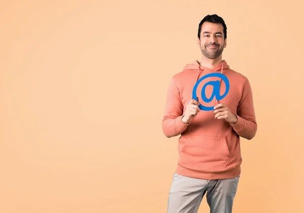 Homem Camisola Rosa Segurando Ícone Ponto Com Fundo Ocre — Fotografia de Stock