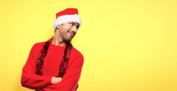 黄色の背景に笑みを浮かべて肩を見てクリスマスの休日を祝っている赤い服の男 — ストック写真