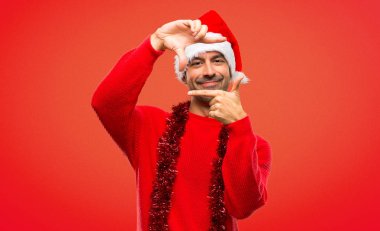 Yüz odaklanarak Noel tatili kutlama kırmızı elbiseler olan adam. Kırmızı zemin çerçeve sembolü