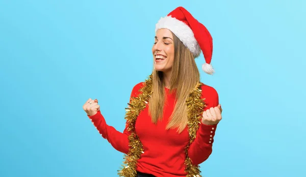勝利を祝うクリスマス休日の服装をして青の背景に賞を獲得した幸せなブロンドの女性 — ストック写真