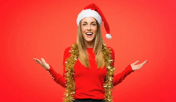 赤の背景で起こっているので驚き式とクリスマス休暇のためドレスアップ金髪女性を期待します — ストック写真