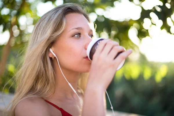 Kulaklık ile müzik dinlemek ve paket servisi olan restoran kağıt bardak sıcak kahve içme genç sarışın kız