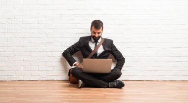 Kalça ve gülen önüne bakıyor, silah ile poz katta oturan onun laptop ile işadamı