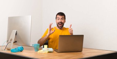 Laptot bir ofis gösteren ok işareti ile çalışan ve jest bir başparmak veren adam
