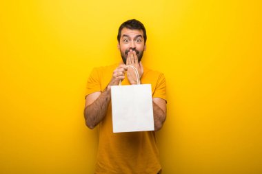 Adam izole canlı sarı renk bir sürü alışveriş torbaları tutarken sürpriz