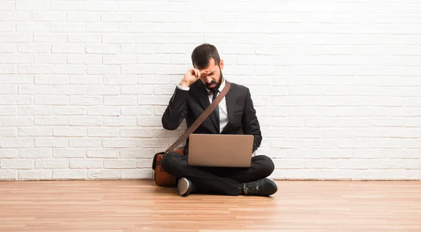 Businessman with his laptop sitting on the floor with tired and sick expression