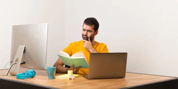 Άνθρωπος Που Εργάζονται Laptot Ένα Γραφείο Διαβάζοντας Ένα Βιβλίο — Φωτογραφία Αρχείου