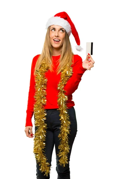 金发碧眼的女人穿着圣诞假期拿着信用卡 在孤立的白色背景思考 — 图库照片