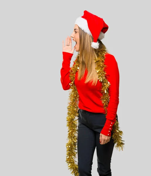 金髪の女性が横に叫び 孤立した灰色の背景上で何かを発表したクリスマス休暇のドレスアップ — ストック写真