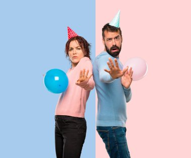 Balonlar ve Doğum günü kaç şapka biraz gergin ve korkmuş elinde cepheye pembe ve mavi arka plan üzerinde uzanan