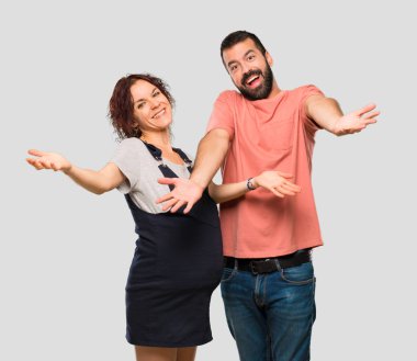 Sunulması ve gelmek davet hamile kadın ile bir çift gördüm. Mutlu izole gri arka plan üzerinde geldi