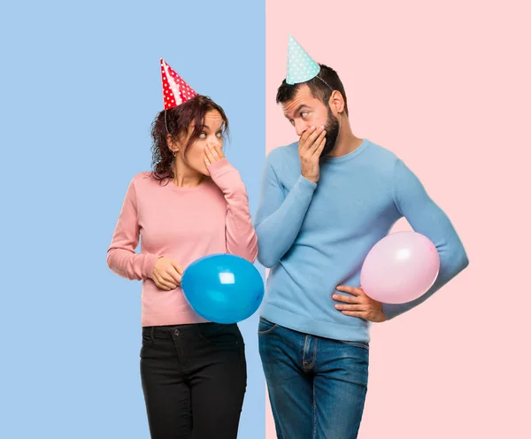 Pareja Con Globos Sombreros Cumpleaños Cubriendo Boca Con Las Manos —  Fotos de Stock