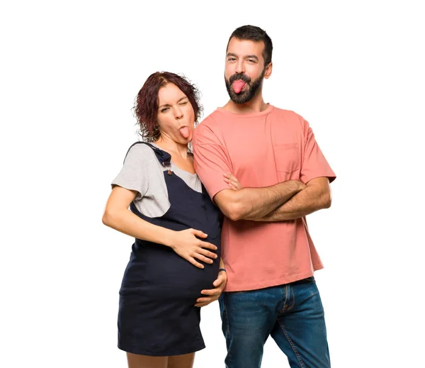 面白いを持つカメラで舌を見せて妊娠中の女性とカップルに見える分離の白い背景の上 — ストック写真