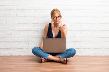 Sunulması ve beyaz tuğla duvar arka planda gelmek davet onu laptop ile katta oturan sarışın kız