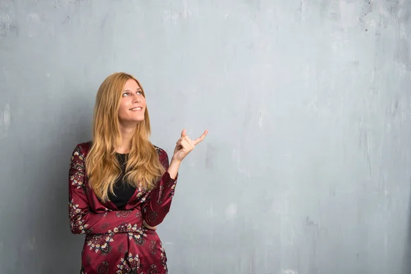 Блондинка Вказує Індексним Пальцем Чудову Ідею Дивиться Фактурний Фон Стіни — стокове фото