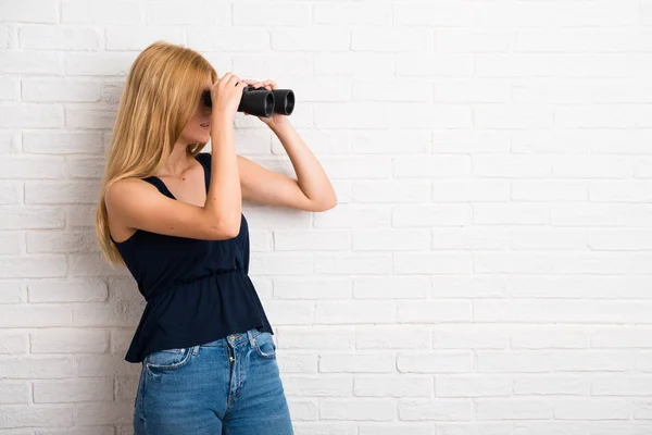 Chica Rubia Con Prismáticos Negros Sobre Fondo Pared Ladrillo Blanco —  Fotos de Stock