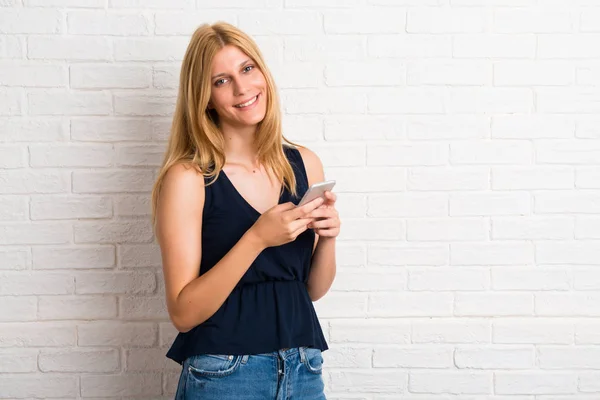 Blonde Girl Using Mobile Phone White Brick Wall Background — Stock Photo, Image