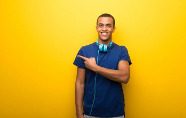 Afro-Amerikan tarafına işaret sarı zemin üzerine mavi t-shirt bir ürün sunmak için adamla
