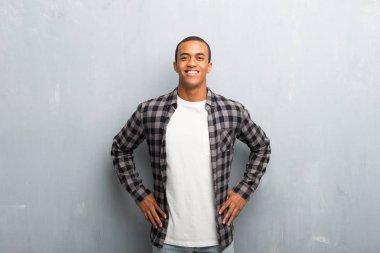 Silah, kalça ile poz ve önüne bakarak gülen kareli gömlek ile genç Afro-Amerikan adam