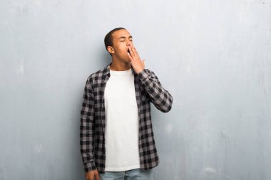 Esneme ve el ile geniş açık ağız kapsayan kareli gömlek ile genç Afro-Amerikan adam