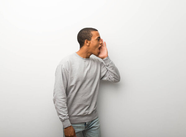 African american man on white wall background shouting with mouth wide open to the lateral