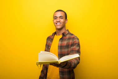 Bir kitap ve birine vererek canlı sarı zemin üzerine genç Afro-Amerikan adam